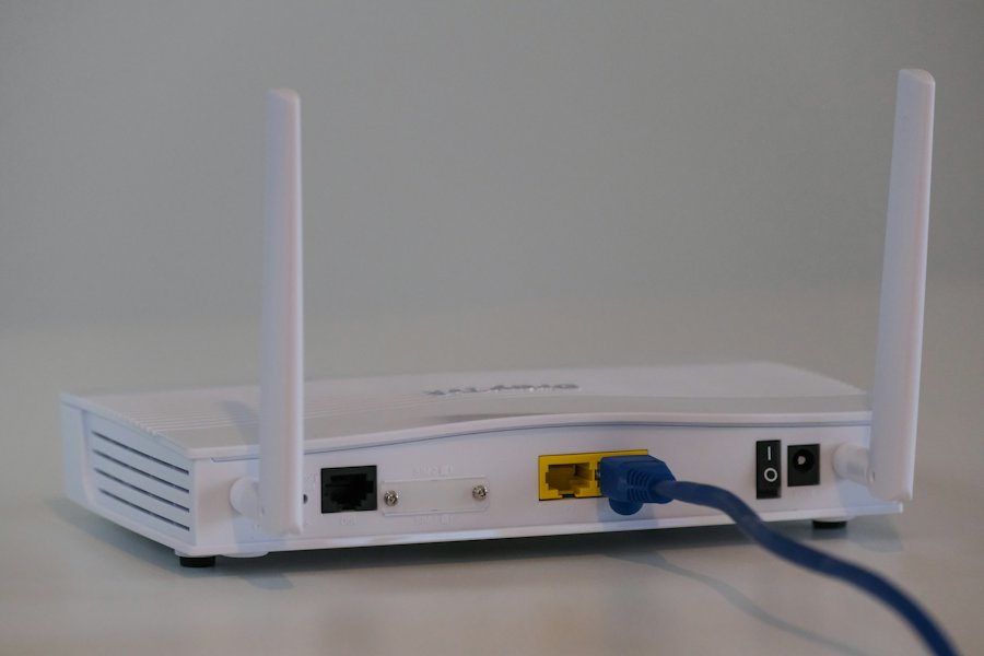 Fehér otthoni router hálózati kábellel, közelről